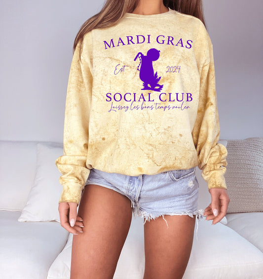 yellow tye die sweater with purple writing that says mardi gras socialclub