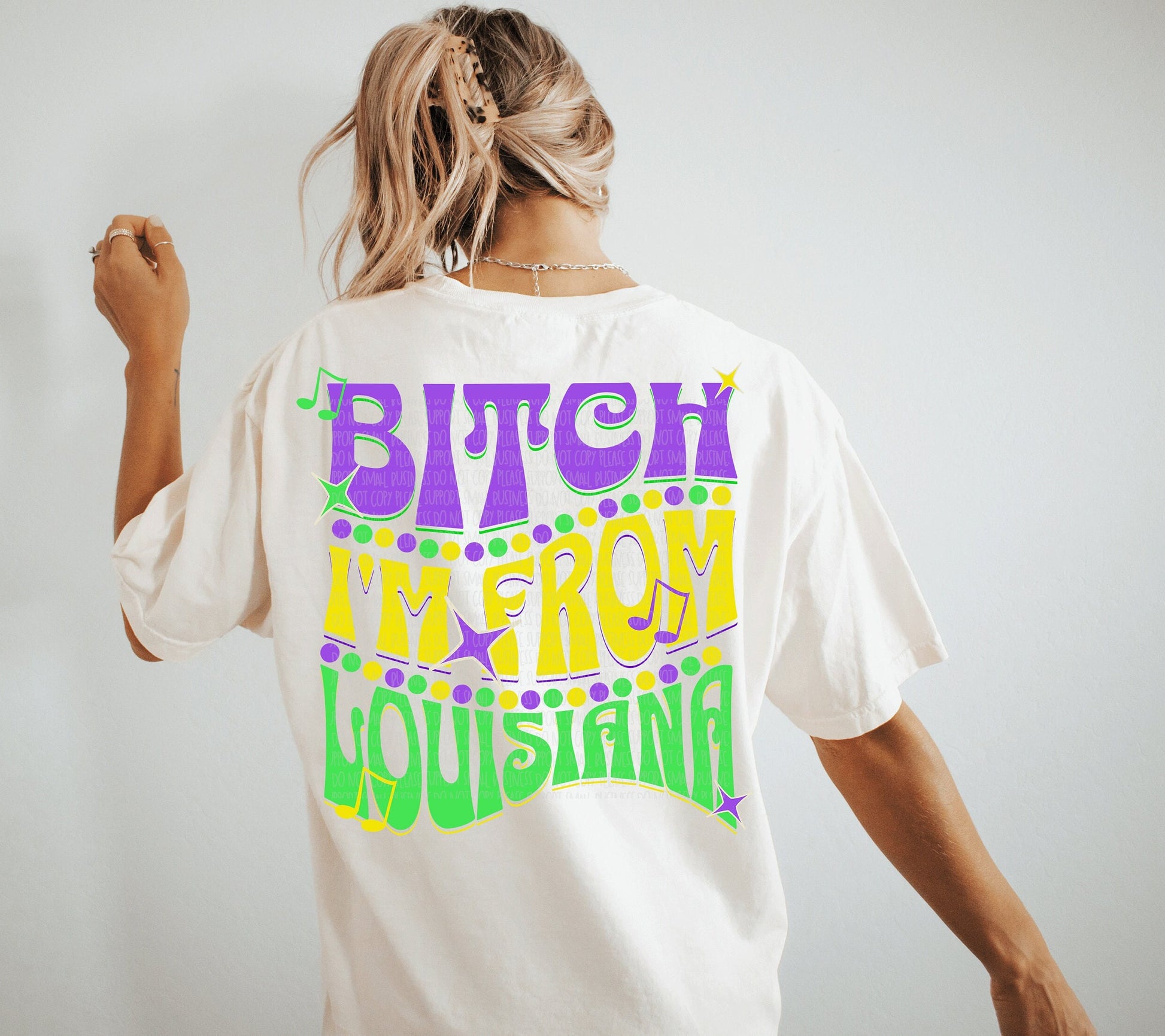 Ivory tee shirt that says bitch im from louisiana in purple green and gold for mardi gras